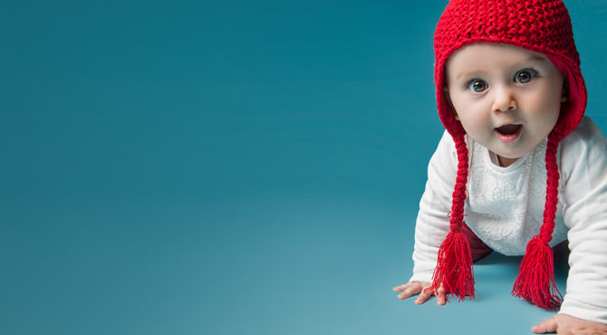 Photo of baby crawling with a red hat on