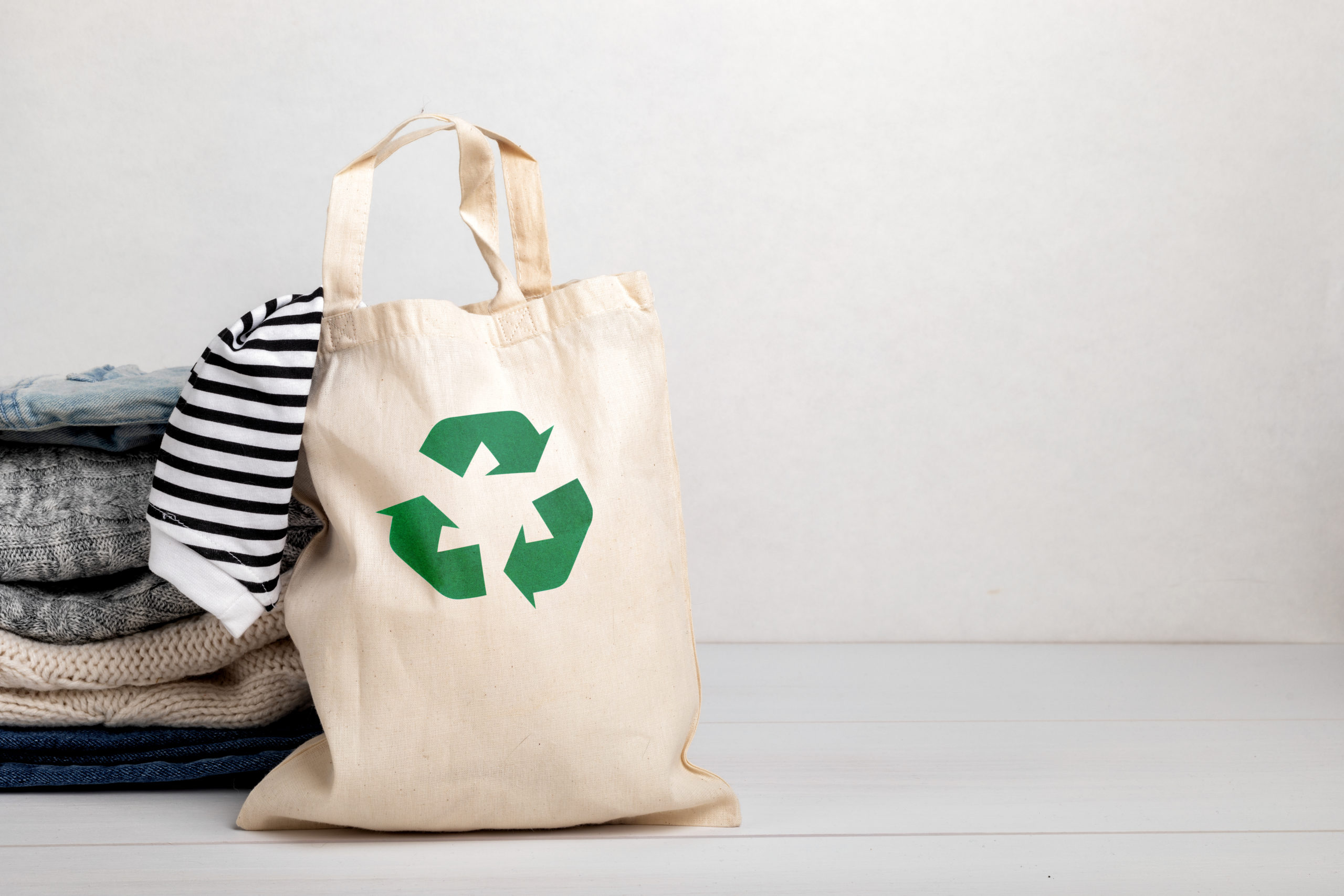 economia circular, ecobag com símbolo de reciclagem com roupas