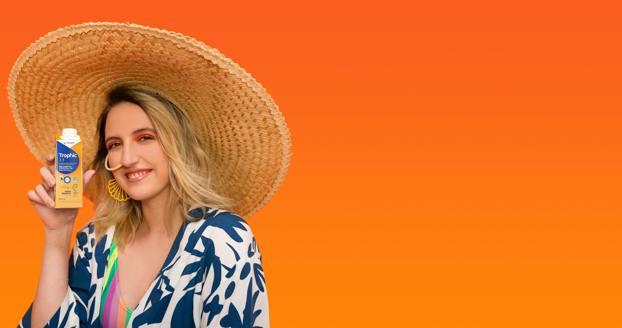 A woman wearing a sun-hat and a nose-tube, holding a juice-box style container of medical nutrition.