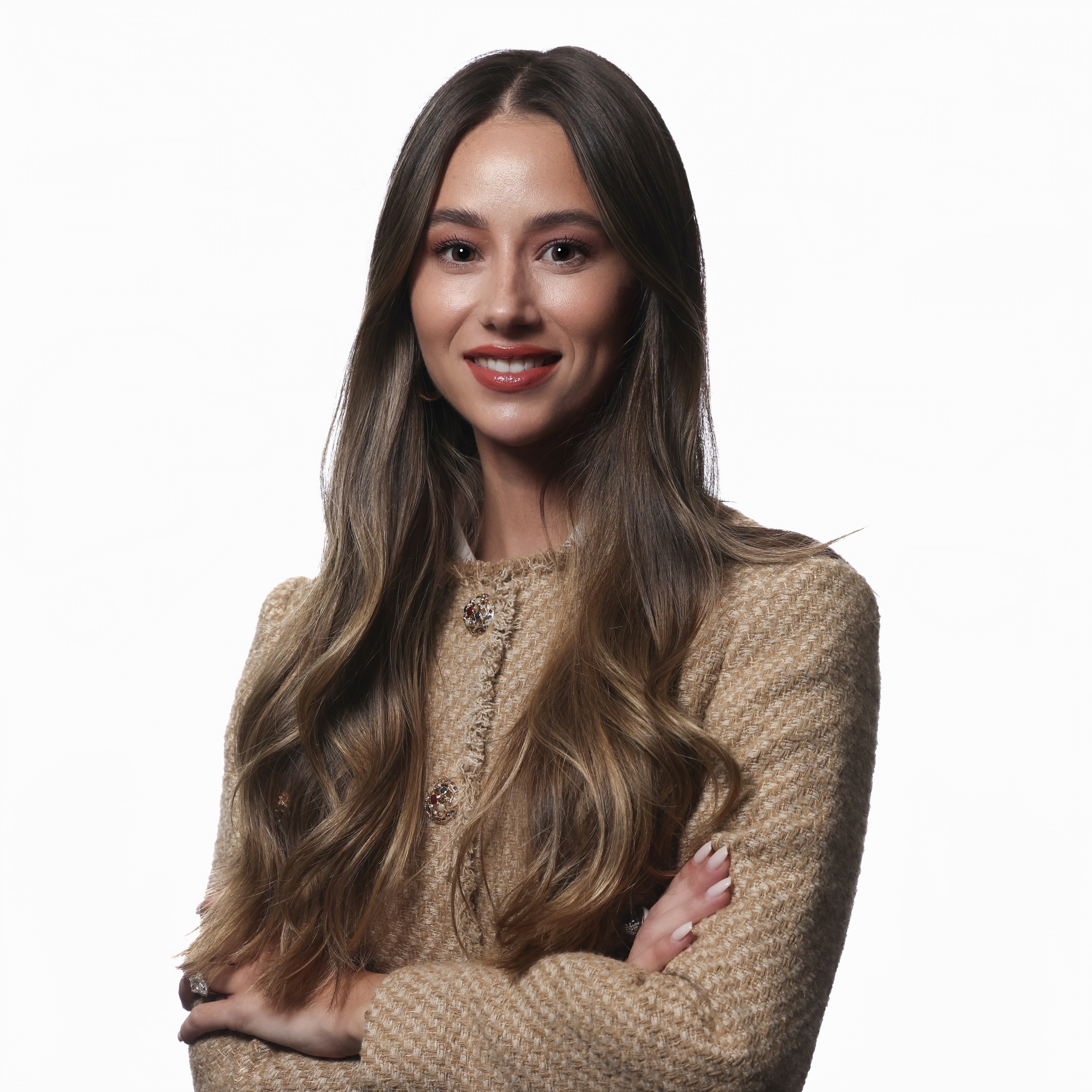 A woman with long brown hair, wearing a beige textured jacket, stands with her arms crossed and smiles at the camera against a white background, exuding confidence and style perfect for any State of Activewear look.